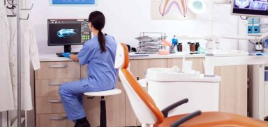 Stomatology office with modern equipment and nurse wearing blue uniform working on computer.